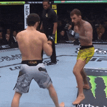 a man wearing venum shorts is fighting another man in a ring