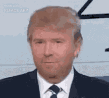 a man in a suit and tie is looking at the camera while wearing a fake donald trump face .