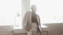 a woman in a suit is standing in front of a desk with her jacket over her shoulder .