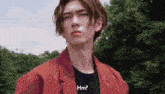 a young man in a red jacket and black shirt says hm .