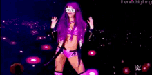 a woman with purple hair and sunglasses is standing in front of a banner that says sasha banks .