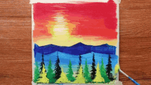 a painting of a sunset with mountains and trees on a wooden table