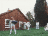 a group of women are standing in a grassy field in front of a house .