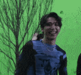 a man wearing a blue shirt and a necklace is laughing and sticking his tongue out .