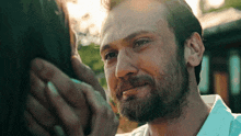 a man with a beard is holding a woman 's hand and looking at her face .