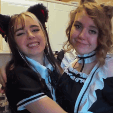 two girls are posing for a picture and one has cat ears on
