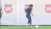 a man is kicking a soccer ball on a field with el gran repte banners in the background
