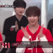 a man in a red shirt is clapping his hands while standing next to a man in a black shirt .