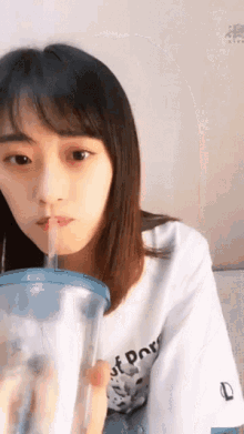a girl is drinking through a straw from a plastic cup