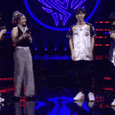 a man wearing a shirt with the number 86 on it is dancing on a stage while a woman applauds .