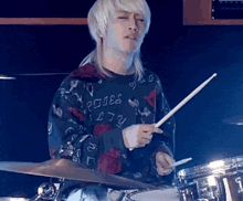 a man playing drums wearing a sweatshirt that says roses