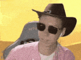 a man wearing a cowboy hat and sunglasses is wearing headphones