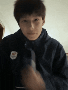 a young man wearing a blue jacket with a badge that says ' beijing ' on it