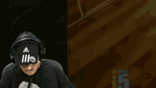a man wearing headphones and an adidas hat looks down