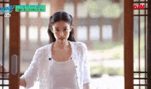 a woman in a white tank top is standing in a doorway .