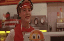 a woman wearing a red hat and bow tie is holding a hamburger in a fast food restaurant .