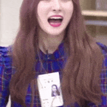 a woman wearing a plaid shirt and a name tag has her mouth open