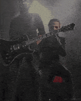 a man in a black suit is playing a black guitar