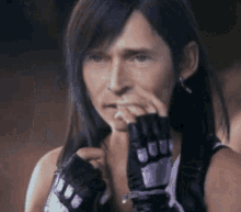 a woman with long hair and gloves is covering her nose