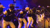 a group of men are dancing on a stage in front of a microphone