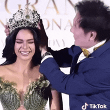 a man in a suit is putting a crown on a woman