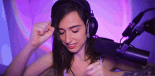 a woman wearing headphones is standing in front of a microphone and smiling .