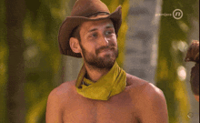 a man wearing a cowboy hat and a yellow bandana is covering his mouth with his hand