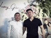 two men are posing for a picture in front of a sign that says " huong giang "