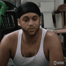a man wearing a black beanie and a white tank top with showtime on the bottom