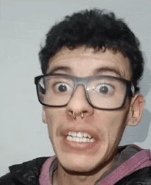 a man with glasses and a nose ring is making a funny face