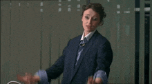 a woman in a suit is giving the middle finger