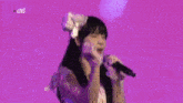 a girl is singing into a microphone on a purple background with the words live on the bottom