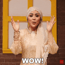 a woman wearing a hijab says wow with her hands up