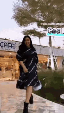 a woman in a tie dye dress stands in front of a cafe