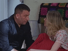 a man in a leather jacket sits next to a woman in a floral shirt