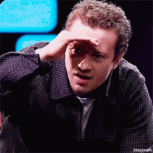 a man in a plaid shirt is covering his eyes