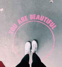 a person is standing in front of a circle that says you are beautiful