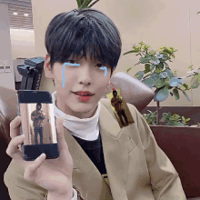 a young man is holding up a cell phone with a picture of a man on it