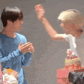 two young men are giving each other a high five in front of a cake .