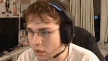 a man wearing glasses and headphones with a microphone is making a funny face .