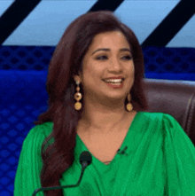 a woman in a green dress is smiling and sitting in front of a microphone .