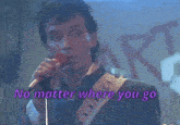 a man singing into a microphone with the words no matter where you go behind him