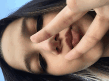 a close up of a woman 's face with her fingers in her mouth
