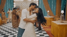 a man is holding a woman in his arms and they are dancing in a room .