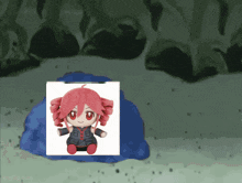 a stuffed doll with red hair is sitting on a blue block