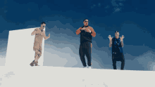 three men are standing on top of a white surface with their hands up in the air