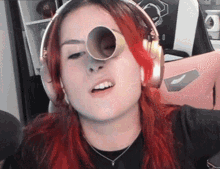 a woman with red hair is wearing headphones and has a cone on her eye .