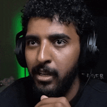 a man with a beard wearing headphones and a shirt that says doer on it