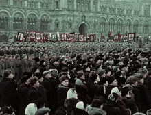 a large crowd of people are gathered in front of a building with a banner that says ' a '