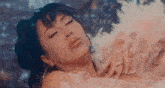 a woman in a white dress is laying down with her eyes closed and a feather boa around her neck .